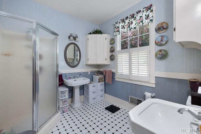 bathroom with an enclosed shower, sink, and tile patterned floors