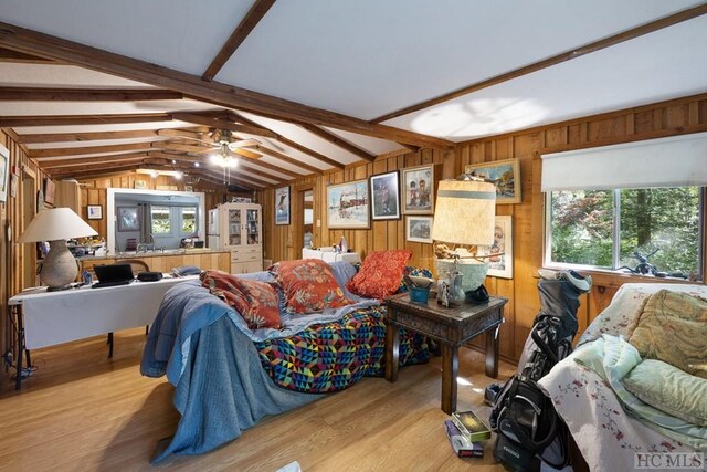 living room with ceiling fan, light hardwood / wood-style floors, lofted ceiling with beams, and wood walls