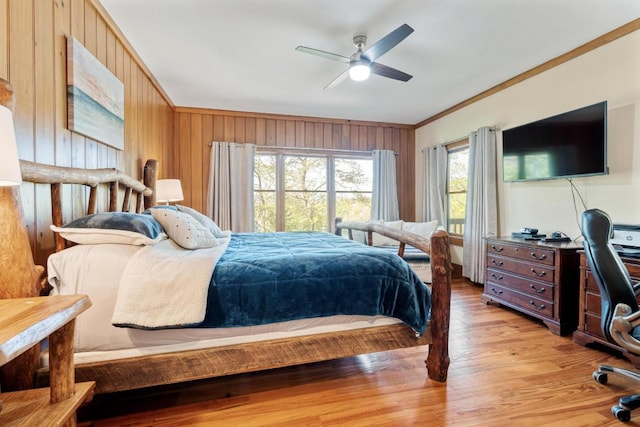 bedroom with ornamental molding, light wood-type flooring, wood walls, and a ceiling fan