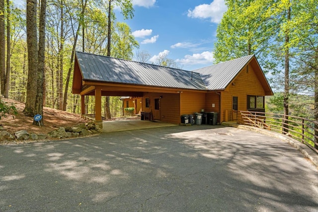 view of front of home featuring asphalt driveway, metal roof, an attached carport, and fence