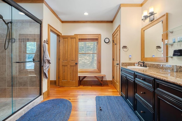 full bathroom featuring a shower stall, wood finished floors, crown molding, vanity, and baseboards