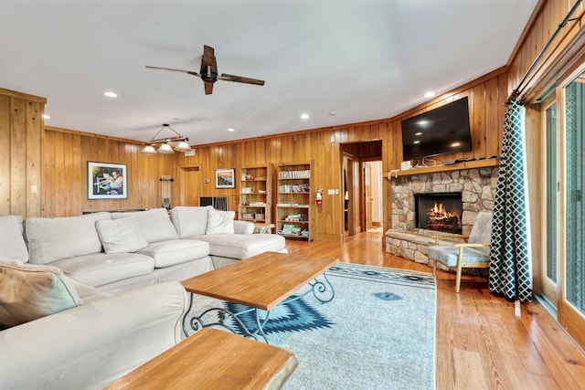 living area featuring wooden walls, a fireplace, a ceiling fan, recessed lighting, and light wood finished floors