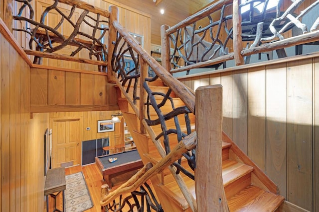 staircase with wood walls, wood finished floors, and a high ceiling