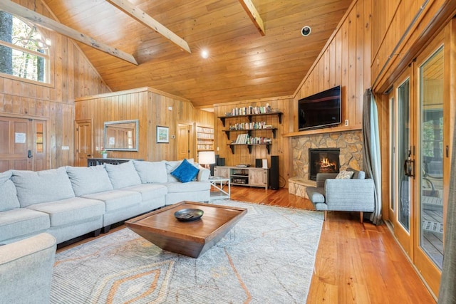 living room featuring wooden walls, light wood finished floors, high vaulted ceiling, wooden ceiling, and a fireplace