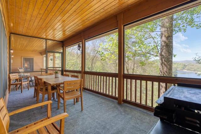 sunroom with outdoor dining space and a water view