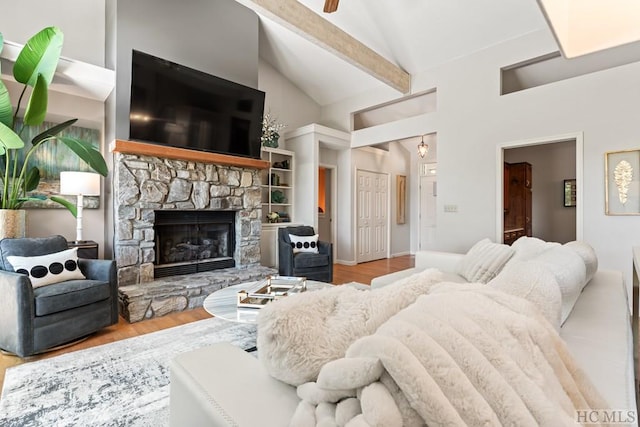 living room with beamed ceiling, a stone fireplace, high vaulted ceiling, and light hardwood / wood-style flooring