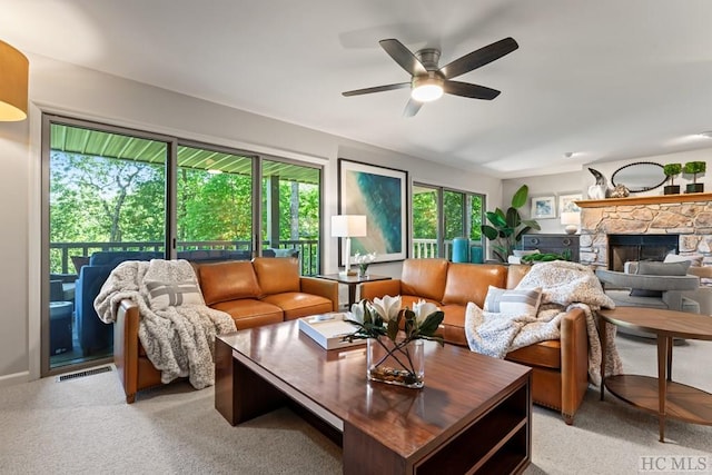 living room featuring a wealth of natural light, a fireplace, light colored carpet, and ceiling fan