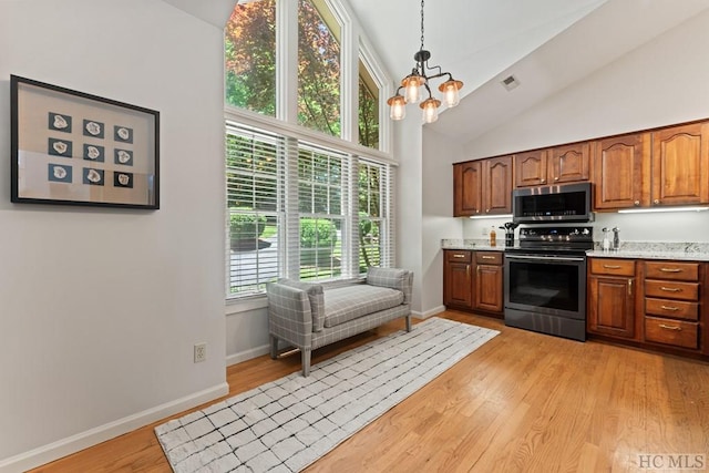 kitchen featuring an inviting chandelier, stainless steel appliances, light stone counters, light hardwood / wood-style floors, and decorative light fixtures