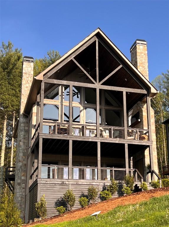 back of house featuring a chimney and a balcony