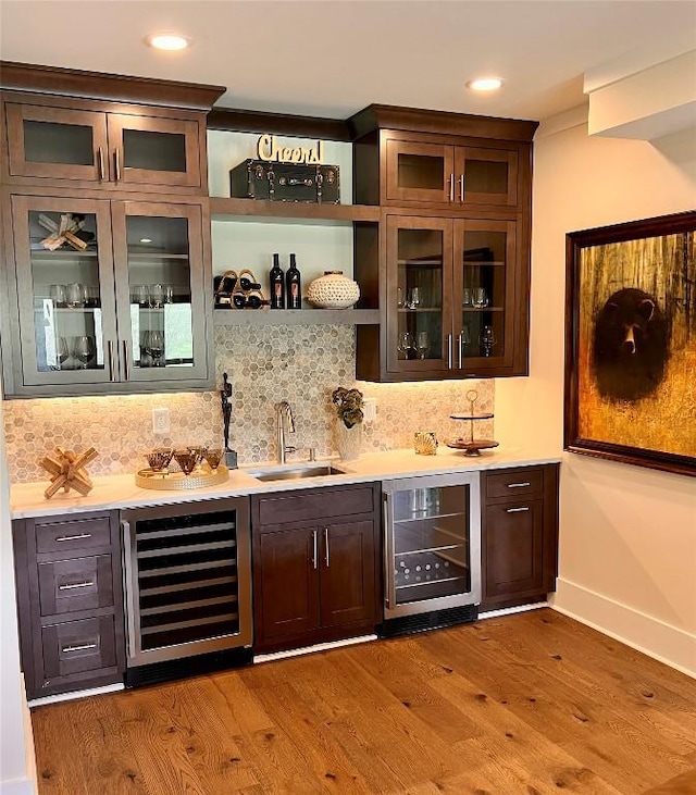 bar featuring a sink, wet bar, wine cooler, and wood finished floors