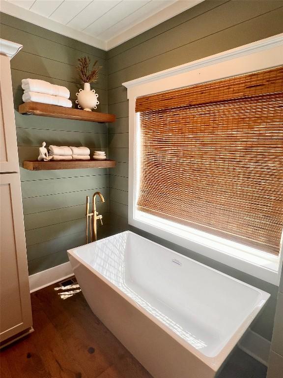 full bathroom with a soaking tub, wood walls, and wood finished floors