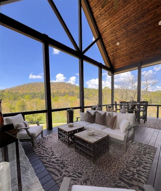 sunroom / solarium with high vaulted ceiling, floor to ceiling windows, hardwood / wood-style flooring, and an outdoor hangout area
