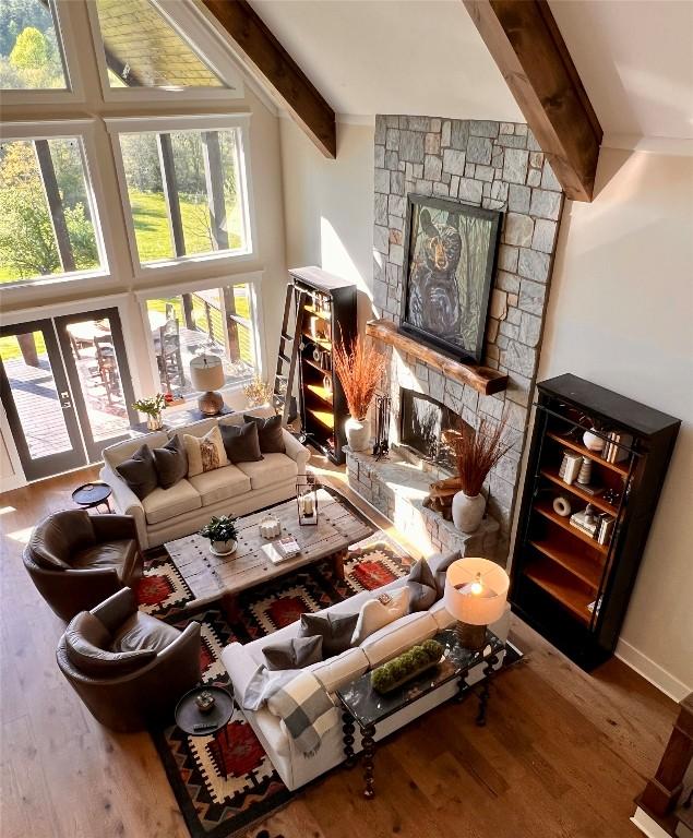 interior space with wood finished floors, a towering ceiling, beam ceiling, and a fireplace