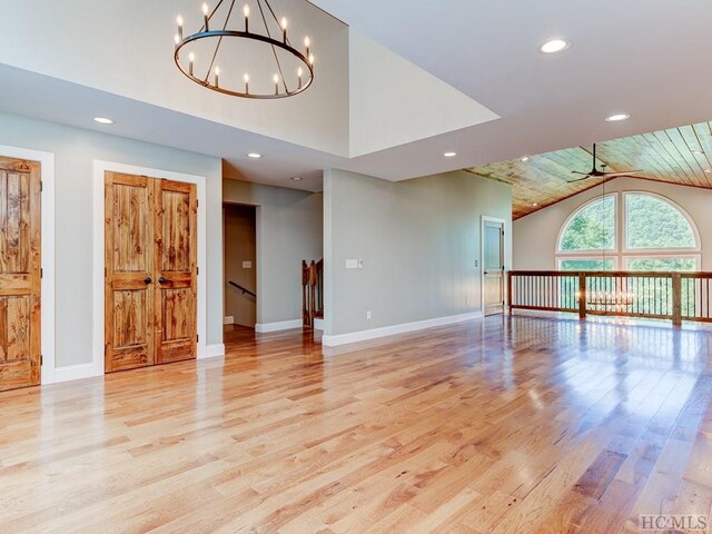 unfurnished living room with wood ceiling, high vaulted ceiling, light hardwood / wood-style floors, and ceiling fan with notable chandelier