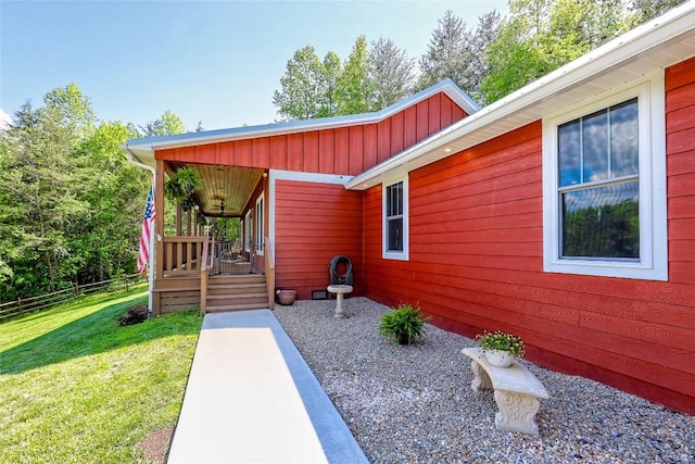 property entrance featuring fence, board and batten siding, and a yard