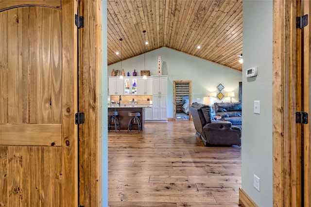 hall with a sink, wood finished floors, vaulted ceiling, and wooden ceiling