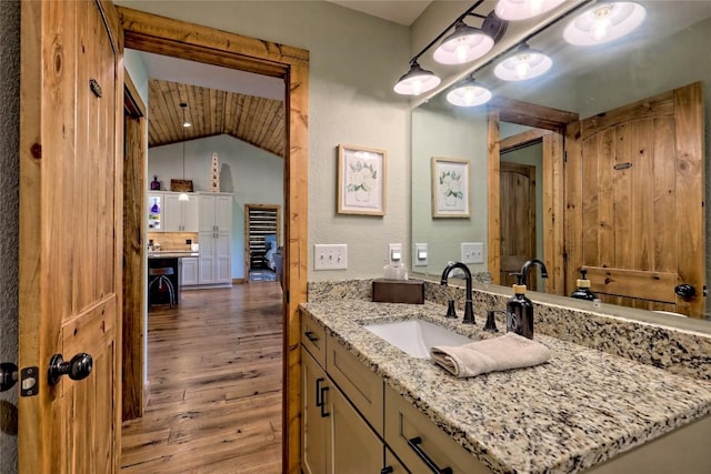 bathroom with wood finished floors, lofted ceiling, and vanity