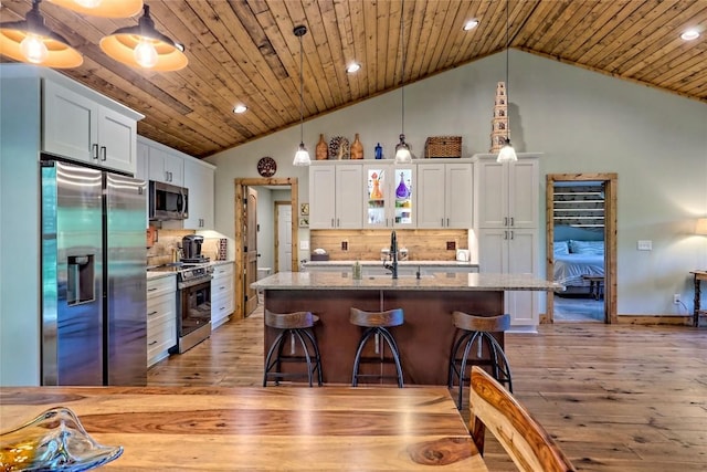 kitchen with appliances with stainless steel finishes, a sink, vaulted ceiling, and light wood-type flooring