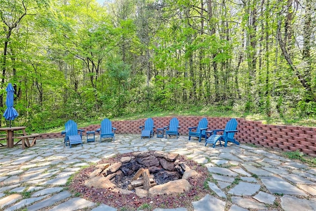view of patio with a fire pit and a wooded view