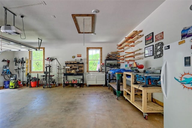 garage with freestanding refrigerator, a workshop area, and a garage door opener