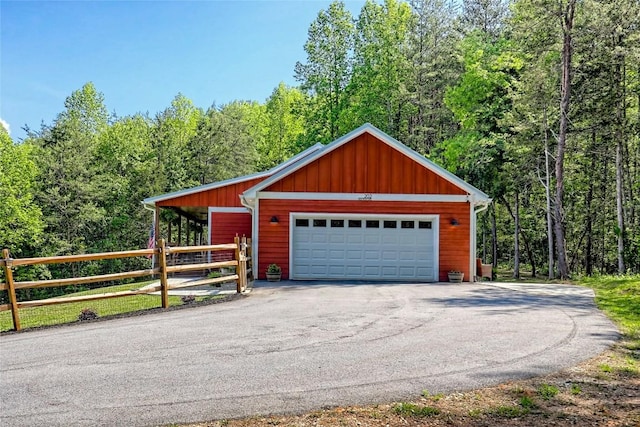 garage featuring fence and a wooded view