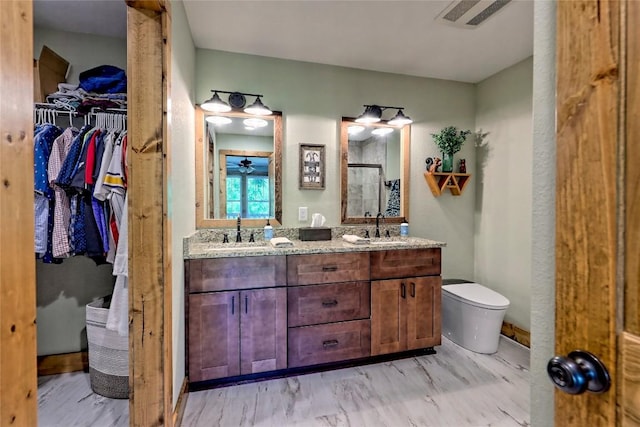bathroom featuring toilet, a walk in closet, a shower stall, and a sink