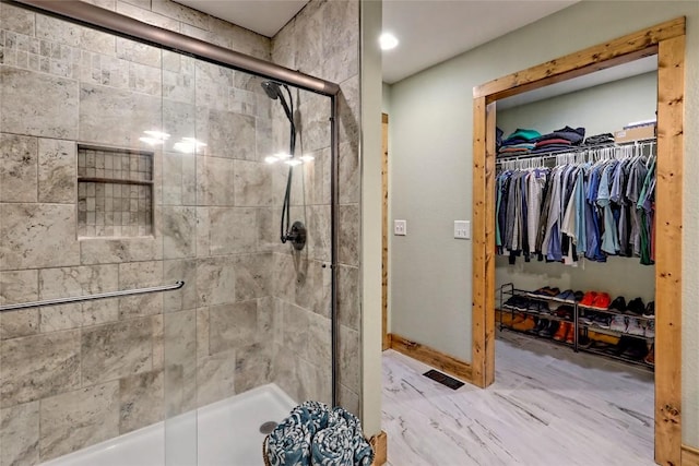 full bathroom featuring a walk in closet, baseboards, and a stall shower