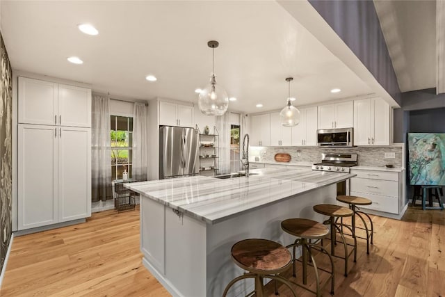 kitchen with light wood-style floors, a sink, white cabinets, and stainless steel appliances