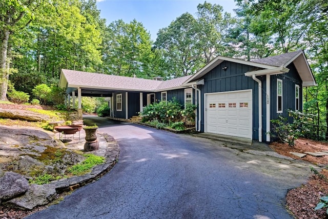 ranch-style house with an attached garage, board and batten siding, and aphalt driveway