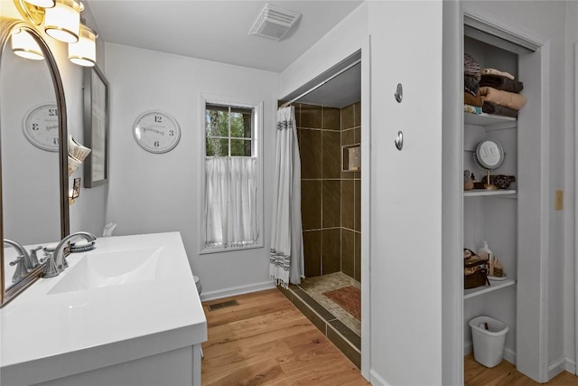 full bath featuring visible vents, a tile shower, and wood finished floors