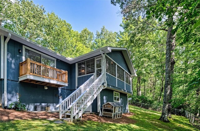 rear view of house with a yard, a sunroom, and stairs