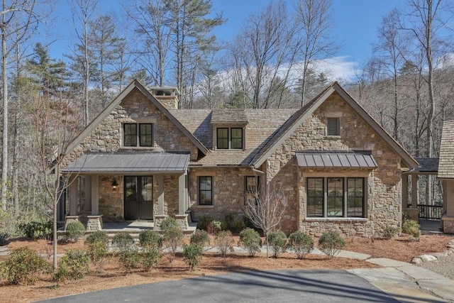 view of front of home featuring stone siding, a standing seam roof, covered porch, and metal roof