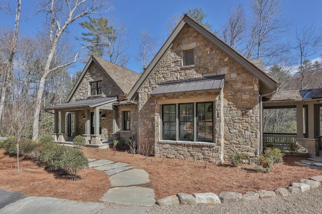 view of front of home featuring stone siding, metal roof, a porch, and a standing seam roof