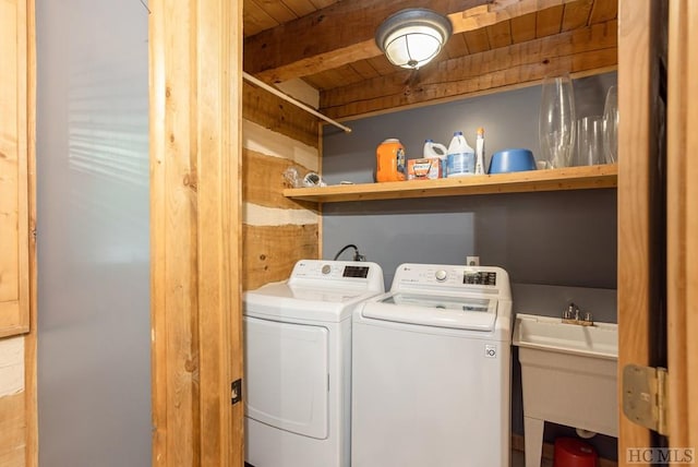 washroom featuring washing machine and dryer, wooden ceiling, and a sink