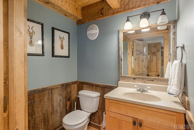 bathroom featuring vanity, toilet, and wood walls