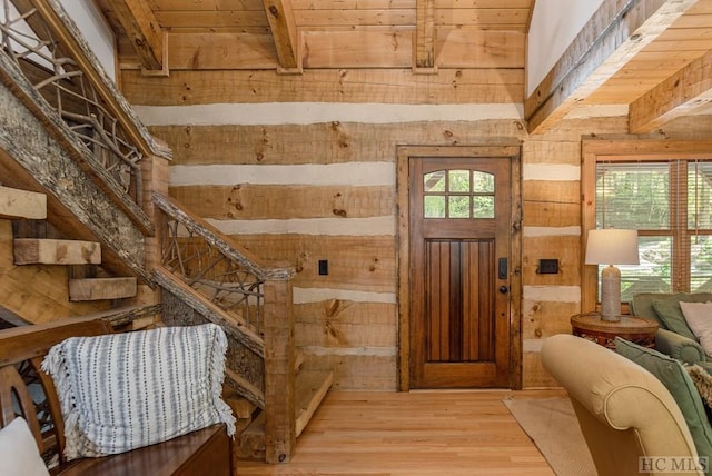 foyer entrance with beamed ceiling, light hardwood / wood-style floors, and wood walls