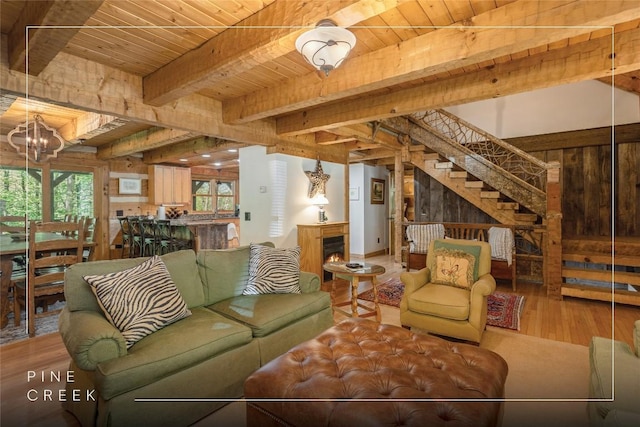 living room with wood finished floors, wooden ceiling, beamed ceiling, a chandelier, and stairs