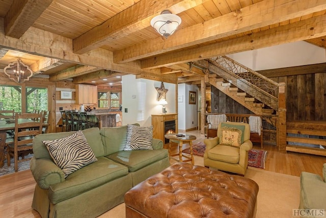 living room featuring wooden walls, beamed ceiling, wood ceiling, an inviting chandelier, and light hardwood / wood-style flooring