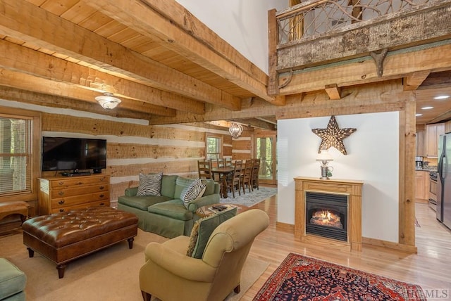 living room with beam ceiling, wooden walls, and light wood-type flooring