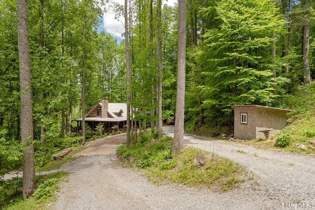 surrounding community with driveway and a wooded view