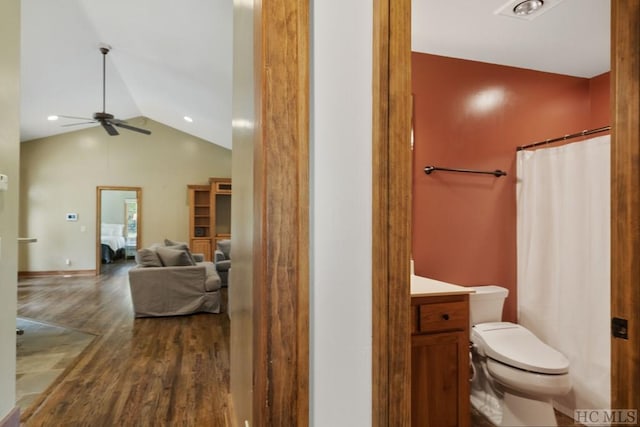 bathroom with vaulted ceiling, vanity, ceiling fan, toilet, and hardwood / wood-style flooring