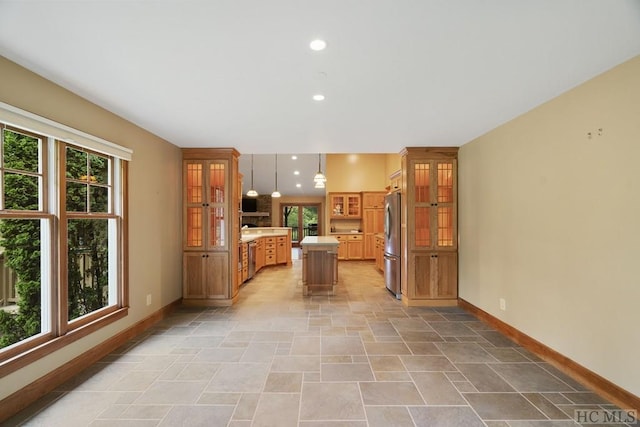 kitchen with a kitchen island, stainless steel refrigerator, and hanging light fixtures