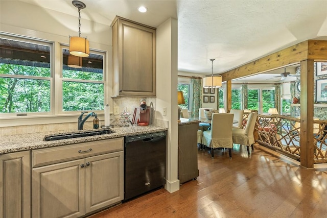 kitchen featuring pendant lighting, dishwasher, sink, light stone counters, and dark wood-type flooring