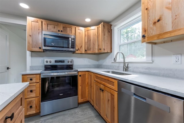 kitchen with appliances with stainless steel finishes, sink, and light hardwood / wood-style floors