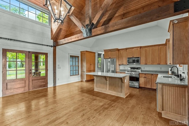 kitchen with sink, decorative light fixtures, a center island, high vaulted ceiling, and stainless steel appliances