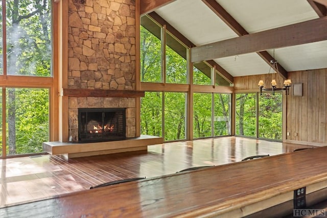 unfurnished sunroom featuring an inviting chandelier, a fireplace, and vaulted ceiling with beams