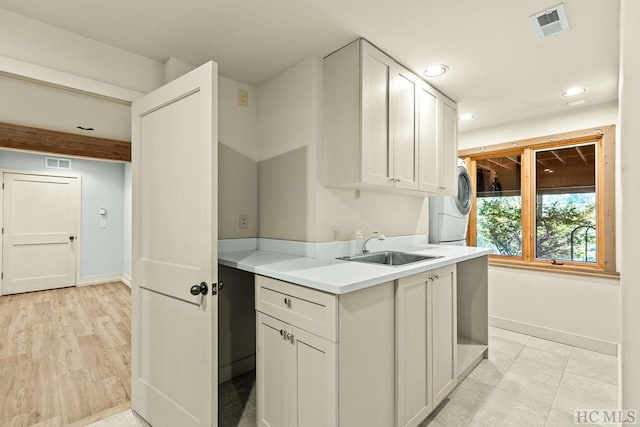 kitchen featuring white cabinetry, washer / dryer, sink, and light hardwood / wood-style flooring