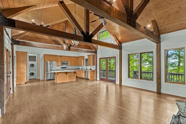 unfurnished living room with beam ceiling, wood ceiling, high vaulted ceiling, and stacked washing maching and dryer