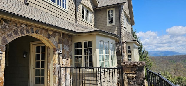 property entrance featuring stone siding, a mountain view, and roof with shingles