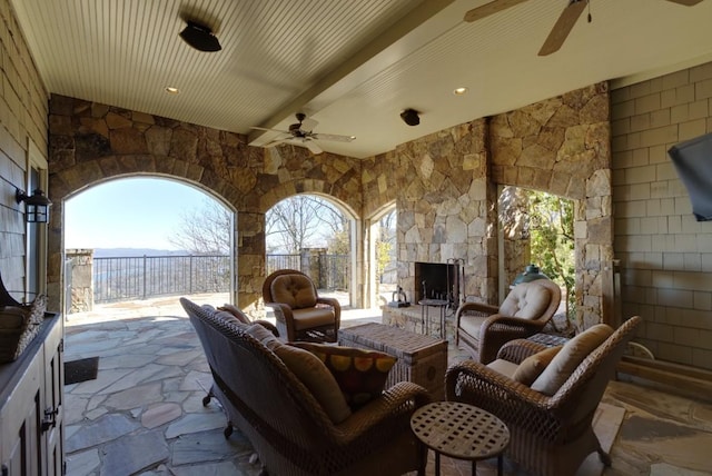 view of patio / terrace with a ceiling fan, an outdoor living space with a fireplace, and fence